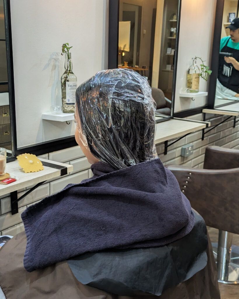 Kaizenケラチントリートメントの薬剤を丁寧に塗布し、25分間自然放置している場面。髪に栄養を浸透させている最中。