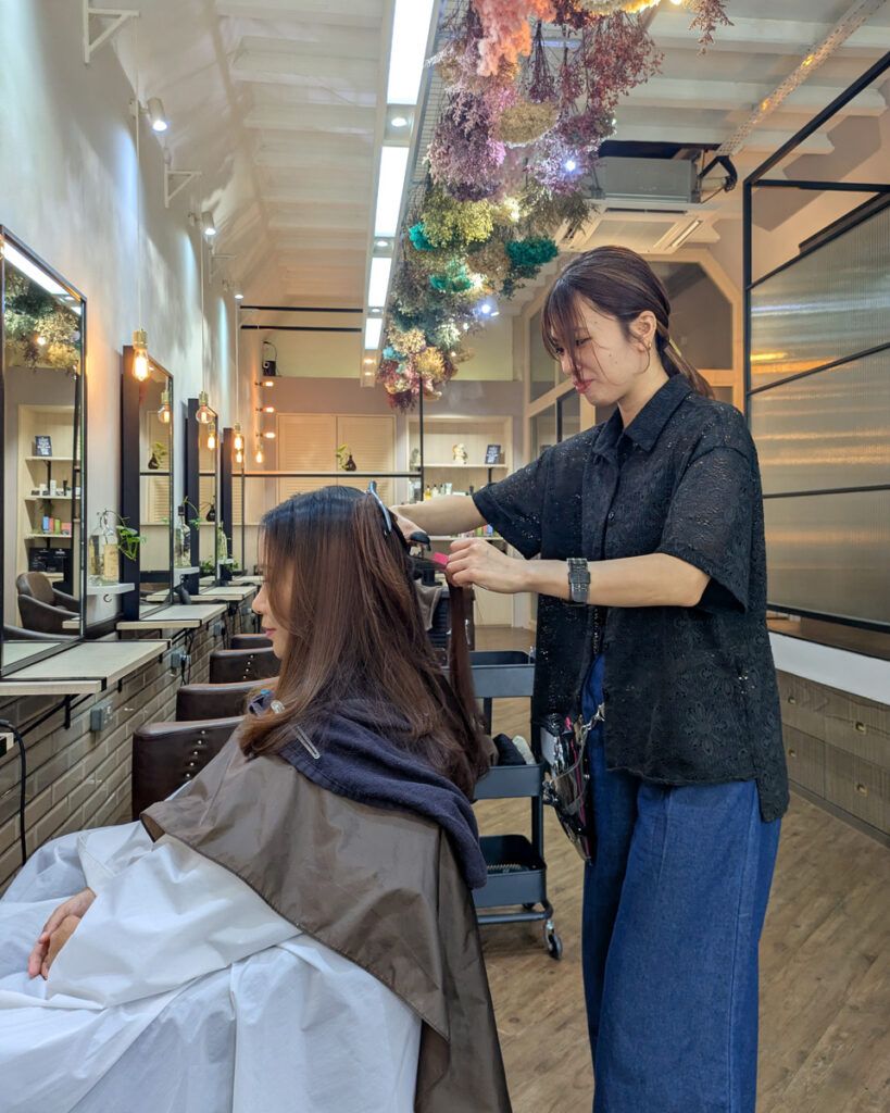 スタイリストMikiさんが丁寧にカウンセリングを行う様子。リバーバレーのショップハウス内、明るい自然光が差し込むHALU HAIR DESIGNの店内。