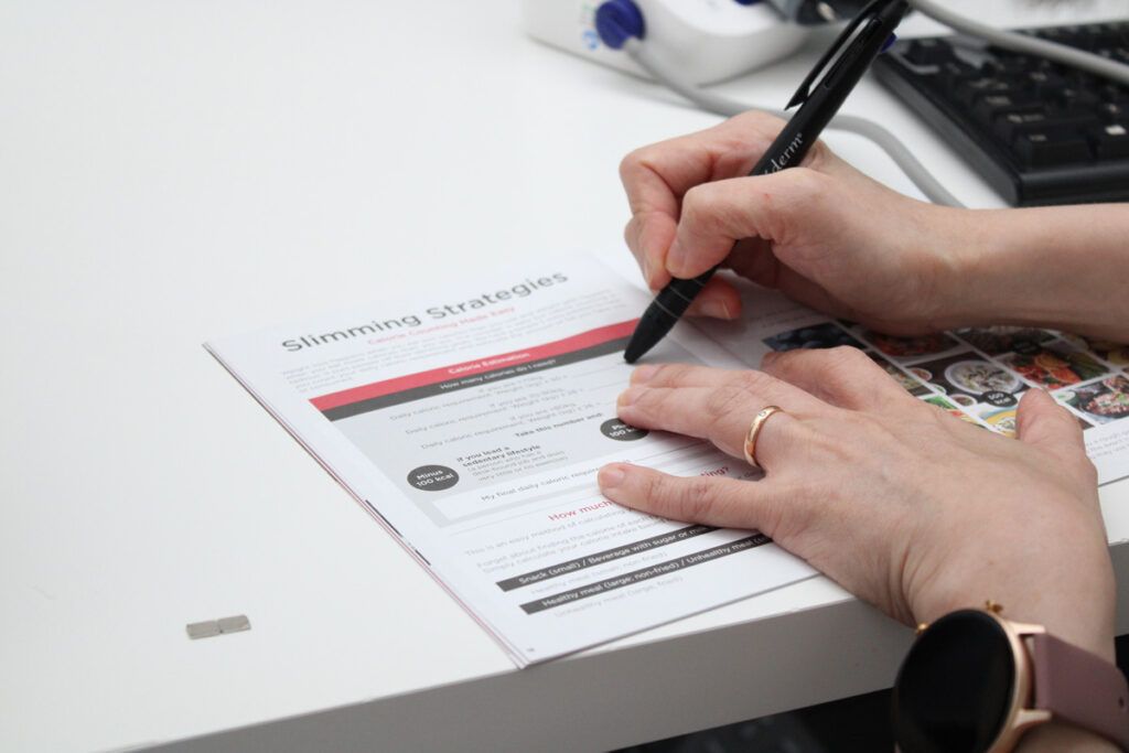 体重管理の目標設定シートに記入しながら、具体的なプランを一緒に確認している手元の様子。